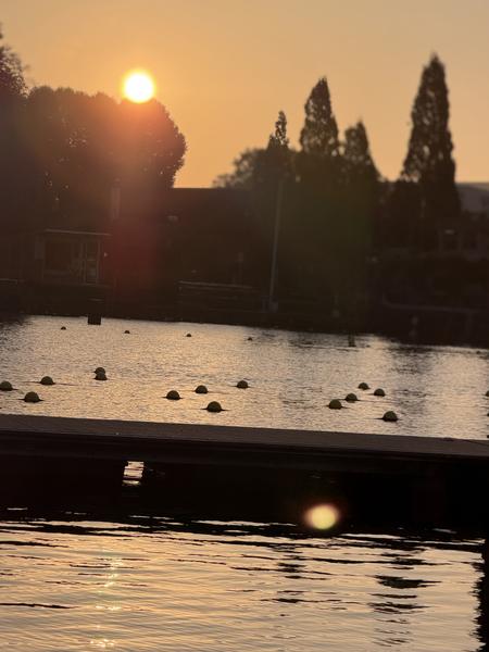 The photo captures a beautiful golden hour sunset over the water at Kade West, Marineterrein, Amsterdam
